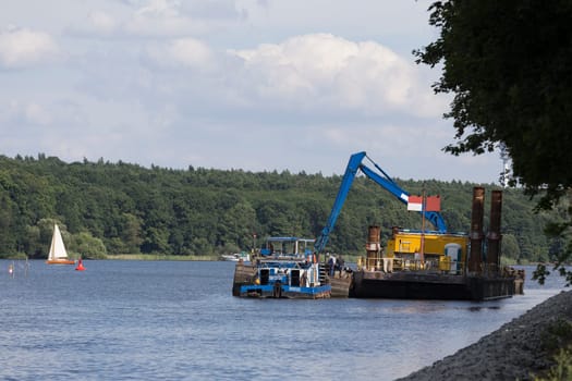 Ship lies next to an excavator that dredges the channel