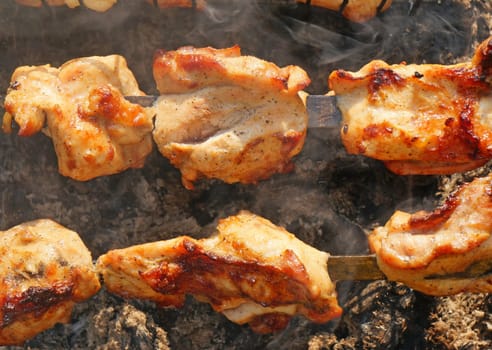 Chunks of turkey on a spit in the smoke