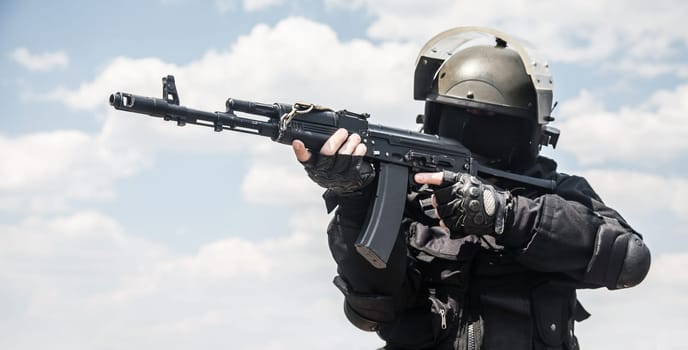 Spec ops soldier in black uniform and face mask with his rifle