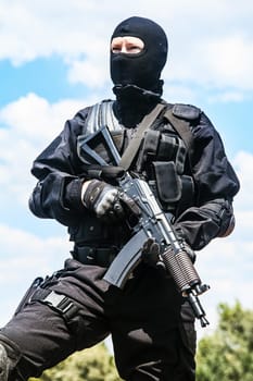 Spec ops soldier in black uniform and face mask with his rifle
