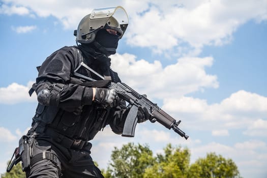 Spec ops soldier in black uniform and face mask with his rifle
