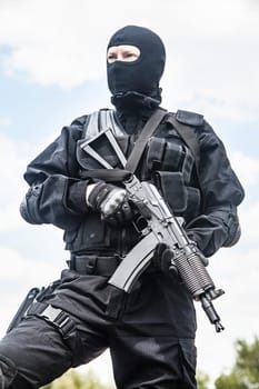 Spec ops soldier in black uniform and face mask with his rifle