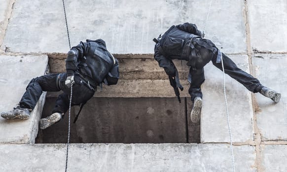 Spec ops soldier in face mask during rope exercises with weapons