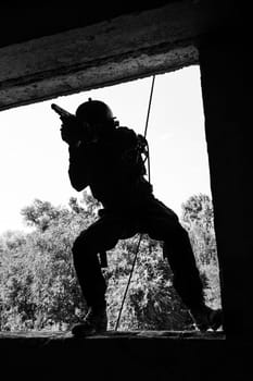 Spec ops soldier in face mask during rope exercises with weapons