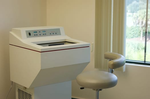 A blood testing machine and leather stool in doctor's office.