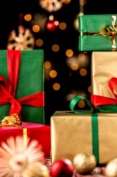 Tightly-framed shot of presents piled-up. Unicolored gift wrapping in red,green and gold. Christmas baubles,stars and twinkles outside the narrow depth of field.