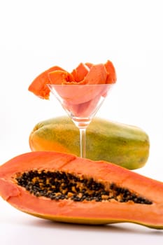 Juicy slices of papaya fruit pulp arranged in a long-stemmed glass. The focus is set on the pulp..