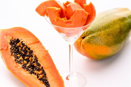 A whole ripe papaya and a half of this tropical fruit. Its succulent pulp surrounds an inner cavity filled with numerous black seeds..