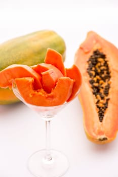 A long-stemmed cocktail glass filled with tangerine papaya slices. The papaya is also called papaw or pawpaw..
