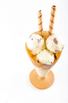 Vanilla ice cream  with wafer in cup on white wooden background