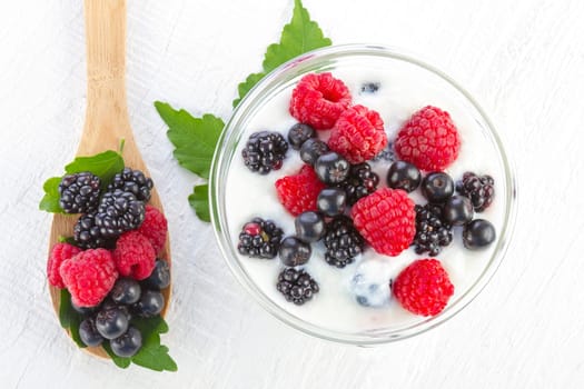 Yogurt with berries in wooden bowl on wooden background