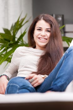 a young happy smiling pretty girl on a sofa with VERY long brown hair