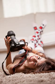 this beautiful smiling sexy nice young girl has a really big DSLR camera reflex in her hands and maybe she's watching pictures or taking them who knows