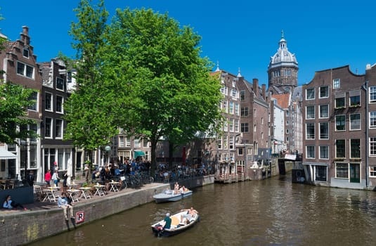 people in a boat on an amsterdam canal. Amsterdam counts 165 canals with a total length of 100 km.
