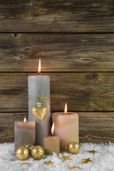Traditional golden christmas decoration with four beige burning advent candles on wooden background.