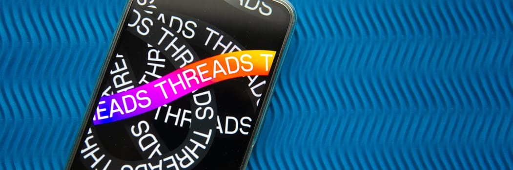 Tver, Russia - July 15, 2023, threads logo on the smartphone screen, on a blue background. The threads icon. The logo of the current application. Threads social network