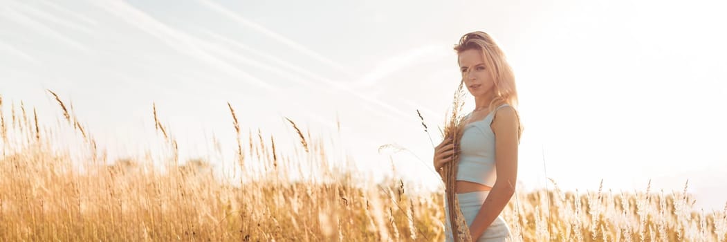 Beautiful blonde woman on a walk in a field with dry grass. A walk in nature, sunset in a field of pampas grass. Life style.