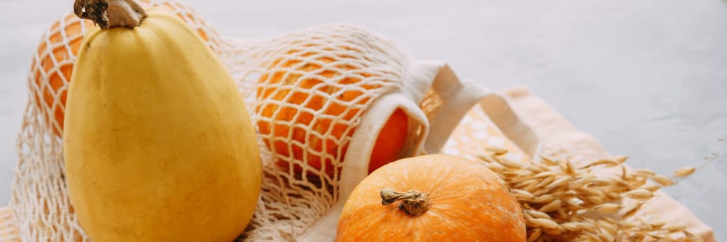 Mesh shopping bag with vegetables. Autumn pumpkin harvest.