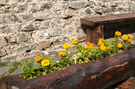Wooden handmade flowerpot and bench on stonewall background