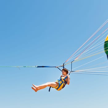 girl parasailing on parachute in blue sky in summer day