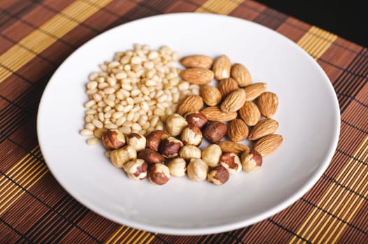 Mixed nuts on a white plate and brown table-napkin