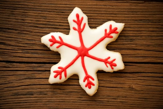 A Red and White Decorated Snowflake Cookie on Wood
