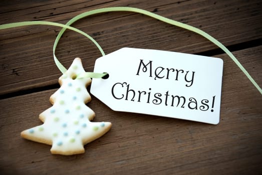 A Christmas Tree Cookie with a Label on which stands Merry Christmas on Wood