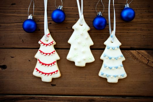 Christmas Tree Cookies and Christmas Balls Hanging on Wooden Background as Christmas or Winter Background