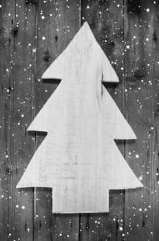 Wooden grey and white christmas tree in shabby style on a wood snowy background for a greeting card.