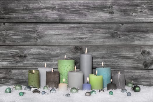 Shabby chic christmas decoration on grey wooden background with different green candles.