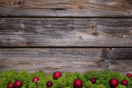 Wooden christmas frame with green moss and red balls on the frame.