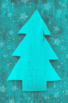 Christmas background in turquoise green color of a handmade carved tree with snow.