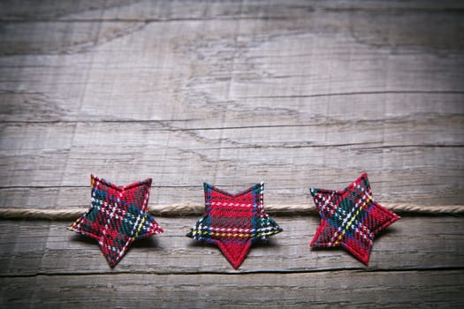 Wooden advent background with three red checked stars as decoration.