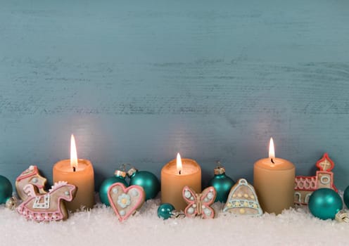 Shabby chic christmas or advent wooden background in mint green or blue color with four burning candles in gold as decoration.