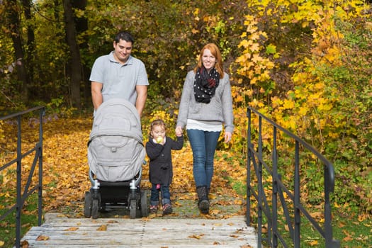 Happy young family in autumn making together a walk in the nature.