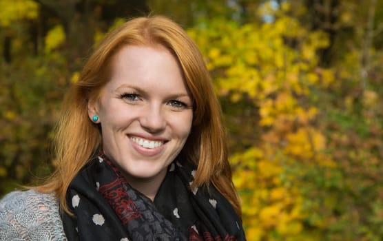 Portrait, Natural red-haired young smiling woman in autumn on a walk.
