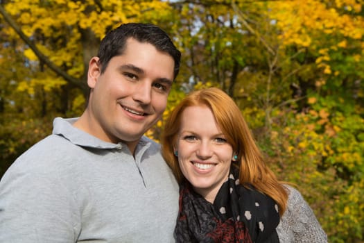 Happy young couple in autumn making a walk in the forest.