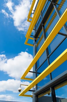 exterior of a modern office building with yellow decorations and a cctv camera attached