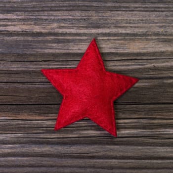One red christmas star of felt on wooden background for decoration.