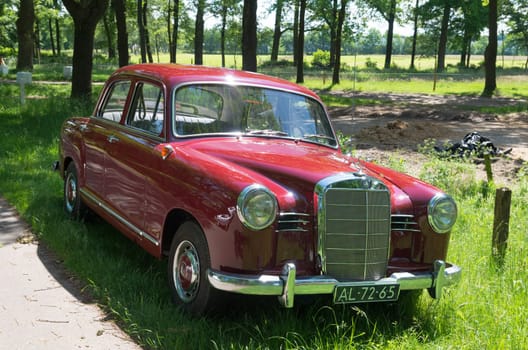 vintage red mercedes car parked along a rural road