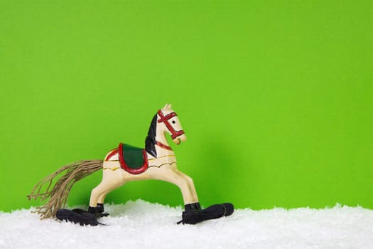 Wooden christmas horse on a green and white background for a greeting card.