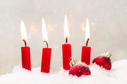 Four burning red candls with christmas ball