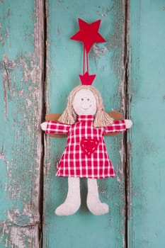 Sewn angel doll hanging on turquoise wooden background for christmas