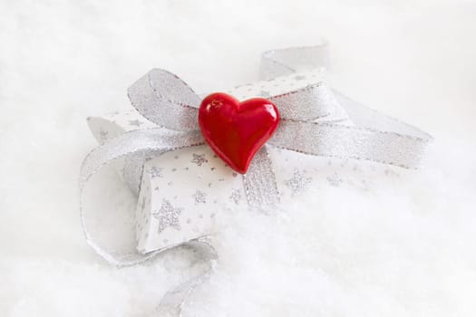 Top view of white and silver present box with red heart for christmas