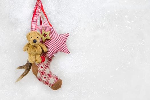 Winter decoration on snowy white background with a red checked star and a teddy bear