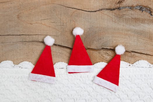 Top view of three Santa hat with crochet strip on wooden background for christmas