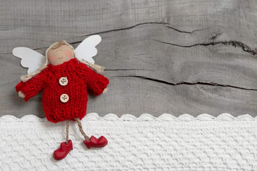 Red christmas or guardian angel on grey wooden background for a greeting card