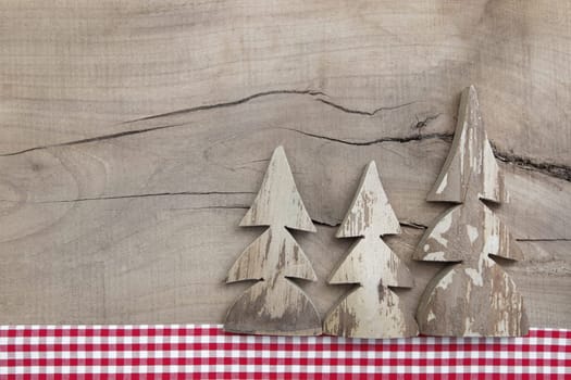 Top view of decoration with three pine tree on wooden background in country style with a red checked frame