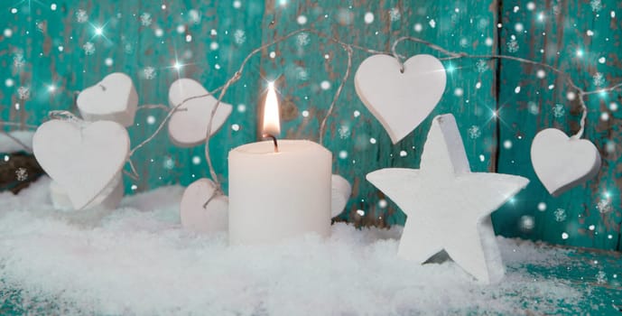 Christmas candle in white with turquoise hearts, wood and snow for decoration