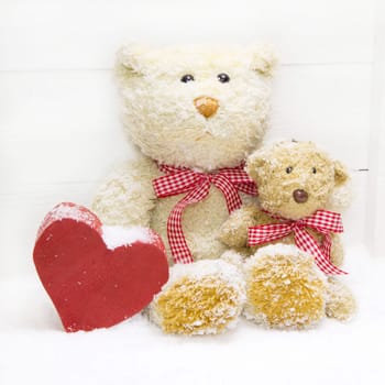 Two teddybear for christmas decoration with a red heard and a red checked ribbon